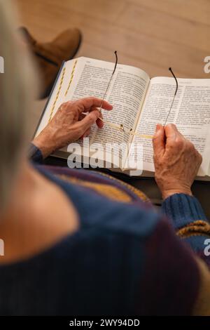 Une personne âgée assise et lisant un livre, tenant les lunettes dans ses mains, Bible Circle, Jesus Grace Chruch, Ludwigsburg, Allemagne Banque D'Images