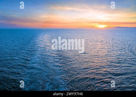 Le bateau se réveille dans la mer au coucher du soleil Banque D'Images