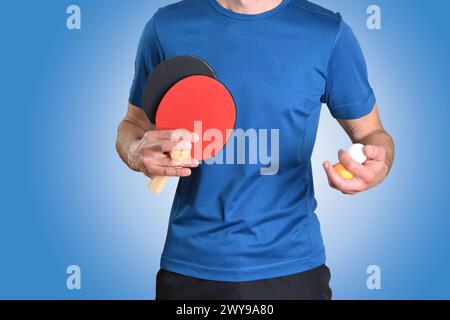 Détail du joueur de ping-pong avec des vêtements de sport et des raquettes et jouer des balles dans les mains sur fond isolé bleu. Banque D'Images