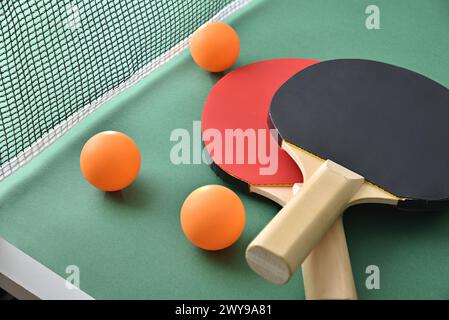 Ensemble de pagaies de ping-pong et balle orange sur la table de jeu verte. Vue surélevée. Banque D'Images