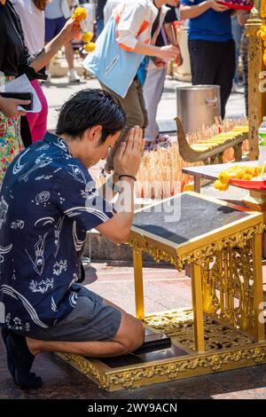 Un homme asiatique prie au sanctuaire emblématique d'Erawan, niché dans le centre-ville de Bangkok. Thaïlande. Banque D'Images