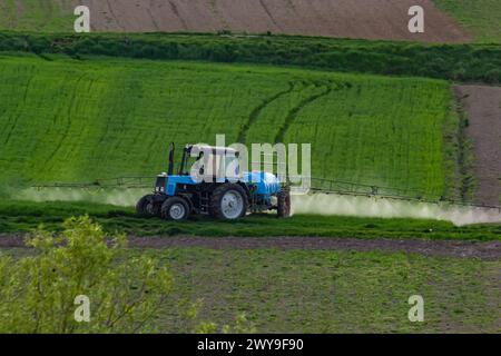 Vue aérienne du tracteur pulvérisant des pesticides dans des champs verts. Banque D'Images