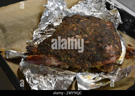 Manger, cuire de la viande délicieuse, cuisse de mouton sur l'os mariné et cuit au four. Un gros morceau d'agneau disposé sur du papier parchemin brun. Banque D'Images