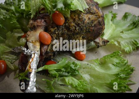 Manger, cuire de la viande délicieuse, cuisse de mouton sur l'os mariné et cuit au four. Un gros morceau d'agneau disposé sur du papier parchemin brun. Banque D'Images