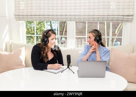 Deux femmes enregistrant un podcast, profondément dans la conversation dans un home studio Banque D'Images