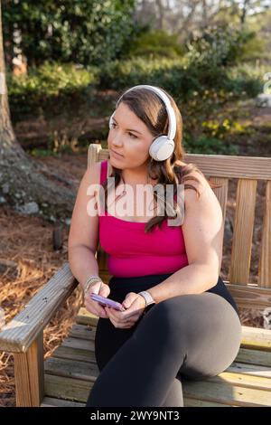 Femme avec des écouteurs utilisant le téléphone à l'extérieur Banque D'Images
