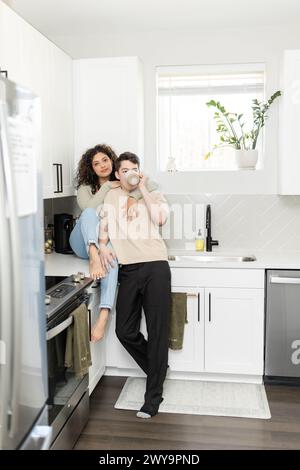 Couple intime apprécie le café dans une cuisine moderne ensoleillée Banque D'Images