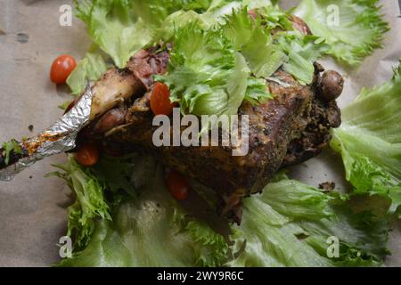 Manger, cuire de la viande délicieuse, cuisse de mouton sur l'os mariné et cuit au four. Un gros morceau d'agneau disposé sur du papier parchemin brun. Banque D'Images