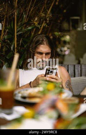 Portrait d'un homme dans un restaurant utilisant le téléphone pendant le déjeuner. Banque D'Images