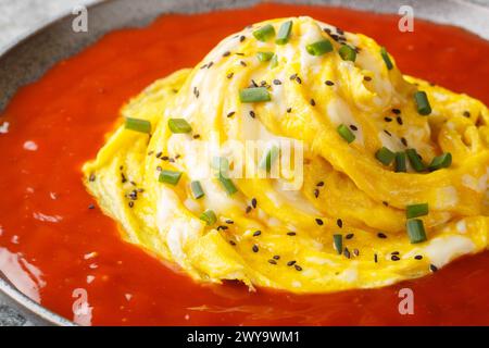 Tornade d'omelette tourbillonnante coréenne sur riz frit et sauce piquante gros plan dans une assiette sur la table. Horizontal Banque D'Images