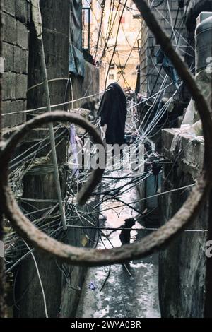 Vue chaotique des fils électriques avec une femme marchant dans la rue du camp de réfugiés de Sabra-Shatila au Liban Banque D'Images