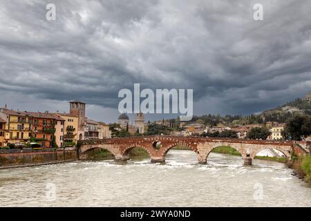 Vue panoramique sur le pont Ponte Pietra à Vérone sur la rivière Adige. Jour pluvieux avec ciel dramatique avec des nuages. Région de Vénétie. Italie Banque D'Images