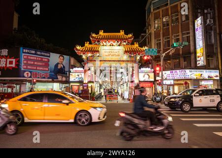 Une scène urbaine la nuit avec des lumières vives des voitures et des panneaux de magasins, mettant en valeur la vivacité de la vie nocturne urbaine de Taipei Banque D'Images