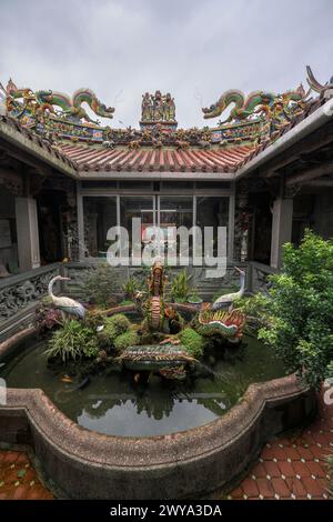 Une cour paisible et calme à l'intérieur du temple Chuen Ji Hall avec un étang à poissons et des sculptures au milieu de la verdure Banque D'Images