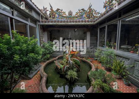 Une cour paisible et calme à l'intérieur du temple Chuen Ji Hall avec un étang à poissons et des sculptures au milieu de la verdure Banque D'Images