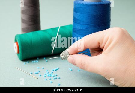 Femme utilisant un protecteur de doigt de coudre en métal ou un doigt de protection à la maison. Outil d'art et d'artisanat. Banque D'Images