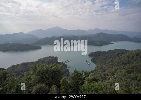 Une vue aérienne tranquille montrant un vaste lac entouré de collines verdoyantes et d'un ciel nuageux Banque D'Images