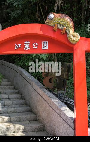 Sculpture caméléon en mosaïque perchée au sommet d'un arc traditionnel rouge vif avec des caractères chinois dans la source thermale de Guanziling Banque D'Images