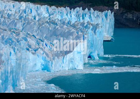 El Calafate, Patagonien, Argentinien - Perito Moreno Gletcher im Nationalpark Los Glaciares. Der Perito Moreno Gletscher gehoert zum patagonischen Eisfeld, dem Campo Hielo sur, der drittgroessten Suesswasserreserve der Welt. Er liegt in der Provinz Santa Cruz am Lago Argentino, dem groessten See des Landes. Der Perito Moreno Gletscher ist bis zu 30 km lang und 5 km breit. Seine Abbruchkante ist an der hoechsten Stelle 70 m hoch. Vom Gletscher abgebrochene kleine Eisberge treiben im Lago Argentino. Der Gletscher gehoert zu den schoensten Sehenswuerdigkeiten Suedamerikas und gilt als eine der me Banque D'Images