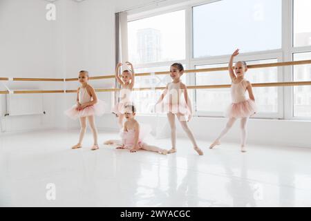 Groupe de petites filles en tenue de ballet effectuant divers mouvements de danse au studio de danse moderne. École de ballet classique. Banque D'Images