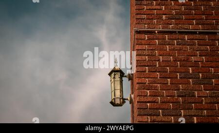 Lanterne en cuivre corrodé montée sur un mur de briques avec nuagdscape Banque D'Images