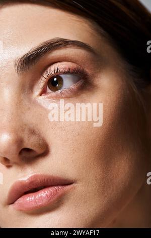 Une jeune femme caucasienne à la peau propre est présentée dans un gros plan, mettant en évidence ses yeux bruns captivants. Banque D'Images