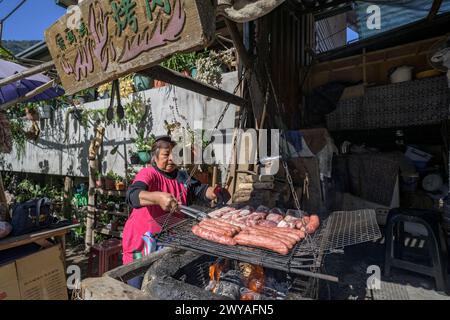 Vendeur de rue en plein air grillant des saucisses sur un barbecue Banque D'Images