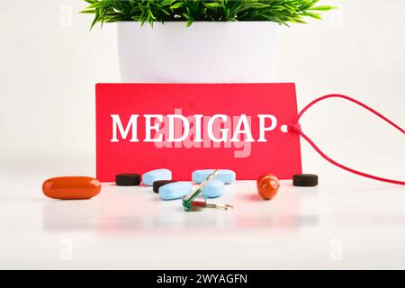 Concept médical. MEDIGAP sur un carton rouge avec des pilules couchées à côté Banque D'Images