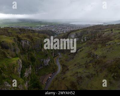 Vue aérienne d'une route sinueuse traversant des falaises vertes spectaculaires sous un ciel orageux Banque D'Images