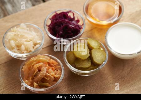 Sélection d'aliments fermentés - kimchi, choucroute blanche et violette, vinaigre de cidre de pomme, cornichons et kéfir dans des bols en verre Banque D'Images