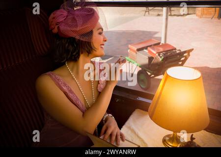 Scène de reconstitution d'une robe de 1920s flapper dame appréciant le thé dans un authentique 1927 compartiment de train à vapeur Banque D'Images