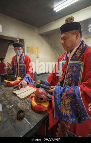 Un chaman traditionnel exécutant un rituel avec des offrandes aux ancêtres sur un autel dans le temple Donggyue Hall Banque D'Images