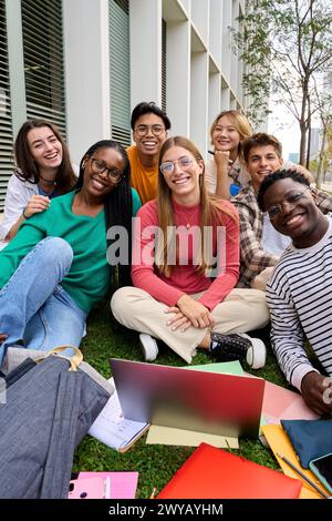 Portrait d'un grand groupe d'amis multiraciaux assis posant souriant avec un ordinateur portable et des cahiers d'exercices Banque D'Images