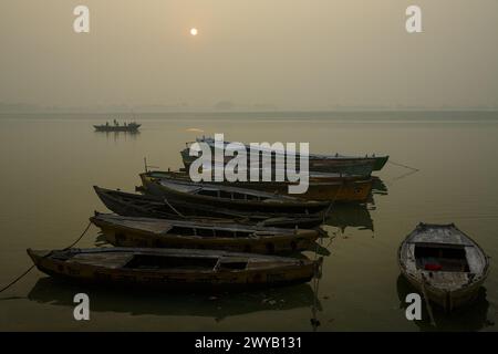 Bateaux amarrés sur le fleuve Gange dans la brume tôt le matin à Varanasi, Inde. Banque D'Images