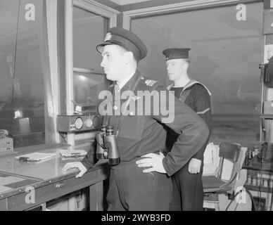 À L'ÉCOLE DES ARTILLEURS TÉLÉGRAPHISTES DE LA ROYAL NAVY AU CANADA. FÉVRIER 1945, YARMOUTH (NOUVELLE-ÉCOSSE). - Le lieutenant CdR Harley, RN, de London (Ontario), commandant en vol, et son messager, NA1 Walker de Leeds, dans la tour de contrôle surplombant le champ de vol. , Banque D'Images