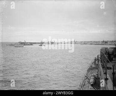 LE HMS HERMIONE EN PATROUILLE DANS L'ATLANTIQUE, ESCORTANT LE SOUS-MARIN HMS REGENT ENDOMMAGÉ PAR LES INTEMPÉRIES. 24 JANVIER 1942, À BORD DU CROISEUR HMS HERMIONE. LE SOUS-MARIN A ÉTÉ EMMENÉ À PONTA DELGADO, UN PORT NEUTRE DES AÇORES PORTUGAISES, POUR 24 HEURES DE RÉPARATIONS. - L'entrée du port de Ponta Delgado. Sur la gauche, on peut voir les navires marchands britanniques et le nouveau quai en construction. , Banque D'Images