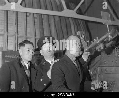 LES MARINS MARCHANDS CHINOIS APPRENNENT LA GUERRE ANTI-AÉRIENNE. OCTOBRE 1941, DANS UN PORT BRITANNIQUE. INSTRUCTION PAR FILM ET BANDE SONORE POUR REPÉRER ET ABATTRE DES AVIONS HOSTILES DONNÉE PAR DES INSTRUCTEURS DE LA MARINE BRITANNIQUE À DES MARINS MARCHANDS CHINOIS DANS UN PORT BRITANNIQUE. - L'instructeur debout derrière un marin marchand chinois au simulateur. Lorsqu'un bombardier Dornie, Heinkel ou Junkers apparaît, il manipule et tire le canon, le résultat étant montré au moyen de lumières. , Banque D'Images