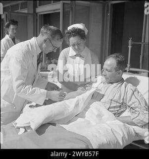 SOINS INFIRMIERS AU SANATORIUM : VIE QUOTIDIENNE AU SANATORIUM BROOMFIELD, CHELMSFORD, ESSEX, ANGLETERRE, 1945 - Une infirmière aide un médecin à prélever du sang d'un patient au sanatorium Broomfield, Chelmsford. Le patient, dans son lit d'hôpital, a été déplacé hors du bâtiment du sanatorium dans le soleil de la «salle» en plein air. , Banque D'Images