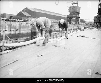 Des ouvriers sont photographiés à bord du HMS Repulse en cale sèche lors de sa remise en état de 1940, travaillant sur les câbles de démagnétisation du navire. Banque D'Images