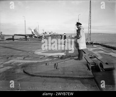 BRAS PNEUMATIQUE FLEET. 7 JANVIER 1942, À BORD DU HMS VICTORIOUS. PILOTES DE CHASSE ET LEURS MACHINES. - Le commandant (F) H C Ranald teste le fonctionnement d'avions de chasse avec chronomètre en main sur le pont d'envol du HMS VICTORIOUS. , Banque D'Images