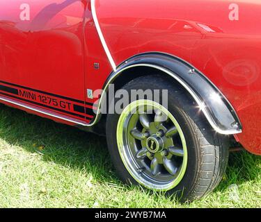 Vue latérale d'une voiture classique Mini 1275 GT en rouge et montrant la roue avant et la garniture latérale Banque D'Images