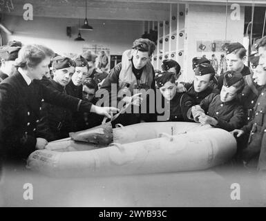 LES GARÇONS DE L'ATC VISITENT LA STATION AÉRIENNE DE LA MARINE ROYALE À BURSCOUGH, POTERIES. 9 FÉVRIER 1945, LORS DE LA VISITE D'UN GROUPE DE GARÇONS ATC À LA BASE AÉRIENNE DE LA ROYAL NAVY. LA VISITE FAISAIT PARTIE DE LEUR FORMATION. - Un cadet remplissant un canot de type observateur pendant qu'un officier Wren explique son contenu. , Banque D'Images