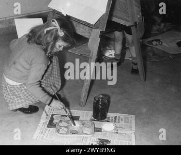 COLONIE POUR ARTISTES DE MOINS DE SIX ANS : ÉVACUÉS À DARTINGTON HALL, TOTNES, DEVON, ANGLETERRE, 1941. - Doreen Hogwood, âgée de 6 ans, évacuée de Gravesend dans le Kent, rassemble de la peinture sur son pinceau à partir d'une palette sur le sol pour continuer sa peinture à Dartington Hall, Totnes, Devon, où elle est logée avec 250 autres enfants. , Banque D'Images