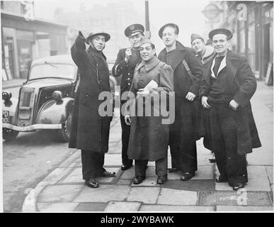 Un policier dirige les soldats et marins français libres à Londres. Un panneau de métro londonien est visible et une voiture est garée à proximité. Négatif photographique, Londres, Angleterre, 1940. Banque D'Images