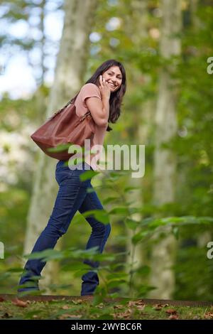 Femme de 35 ans dans le parc parlant avec smartphone. Donostia. San Sebastian. Gipuzkoa. Pays Basque- Espagne. Banque D'Images