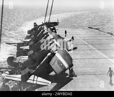 AVEC UN PORTE-AVIONS D'ESCORTE BRITANNIQUE DANS LES EAUX ORIENTALES. MAI 1945, LE CONSEIL D'ACTIVITÉS HMS EMPRESS. - Un croissant blanc moussant marque son tour dans le vent alors que l'IMPÉRATRICE se prépare à voler des chasseurs-bombardiers Grumman Hellcat, pour strafer l'aérodrome tenu par les Japonais dans les îles Andaman. , Banque D'Images