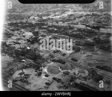 COMMANDEMENT DES BOMBARDIERS DE LA ROYAL AIR FORCE, 1942-1945. - Photographie aérienne oblique à basse altitude du matériel roulant naufragé dans les gares de triage gravement endommagées de Juvisy-sur-orge (France). Les chantiers furent attaqués avec succès par le Bomber Command dans les nuits du 18/19 avril et du 7/8 juin 1944, en soutien à l'invasion alliée de la Normandie. Au premier plan, on peut voir des ouvriers français engagés sur le sauvetage et la réparation de l'épave. , Banque D'Images