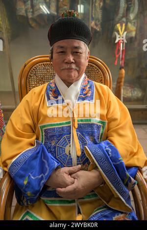 Portrait d'un prêtre atraditionnel en tenue traditionnelle avec des regalia cérémonielles souriant à la caméra Banque D'Images