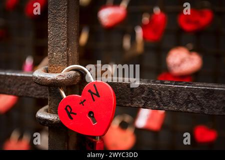 cadenas en forme de coeur rouge attachés aux balustrades pour exprimer l'amour entre deux petits amis Banque D'Images