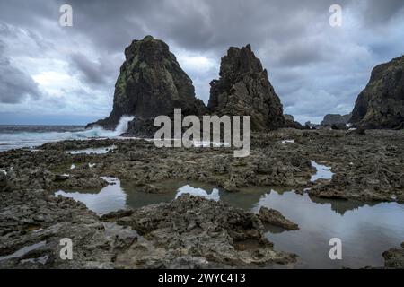 Moody Skies couvre un paysage marin féroce avec de grandes formations rocheuses et des vagues turbulentes qui s'écrasent contre eux Banque D'Images